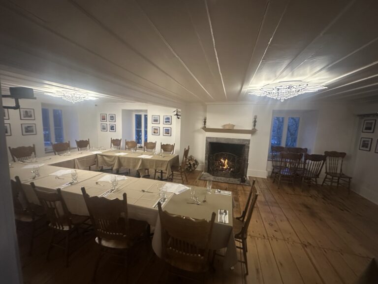 Tables dressées dans la salle de l’Auberge du Manoir avec feu de cheminée.