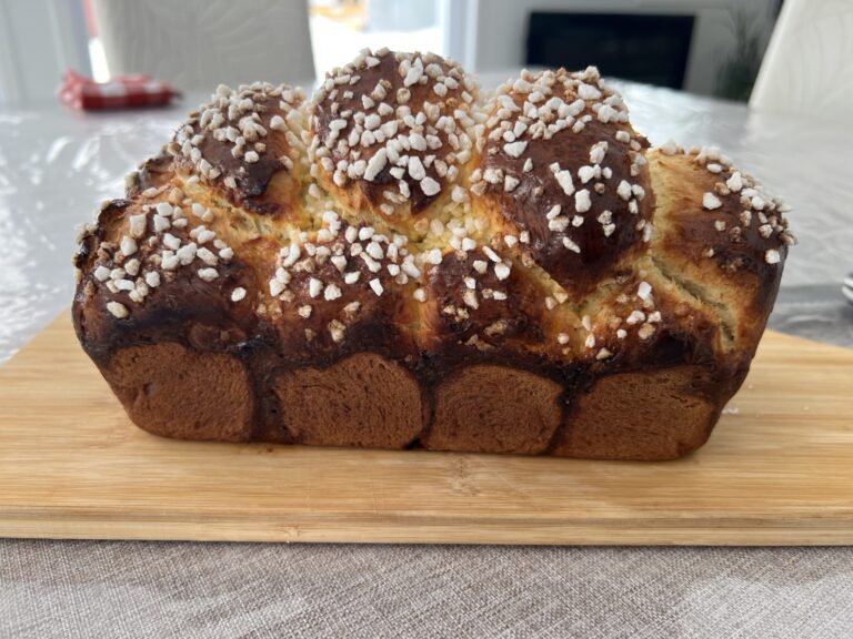Brioche dorée au sucre présentée sur une planche en bois.